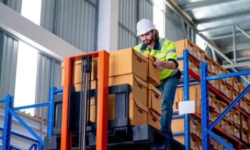 Professional warehouse worker man hold and carry box out from cargo truck that lift up the state